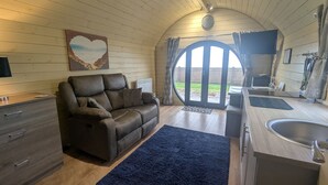 Un salon chaleureux avec un canapé en cuir marron foncé, un meuble en bois et un tapis bleu.