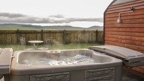 Un bain à remous avec vue sur une clôture en bois et des collines lointaines.