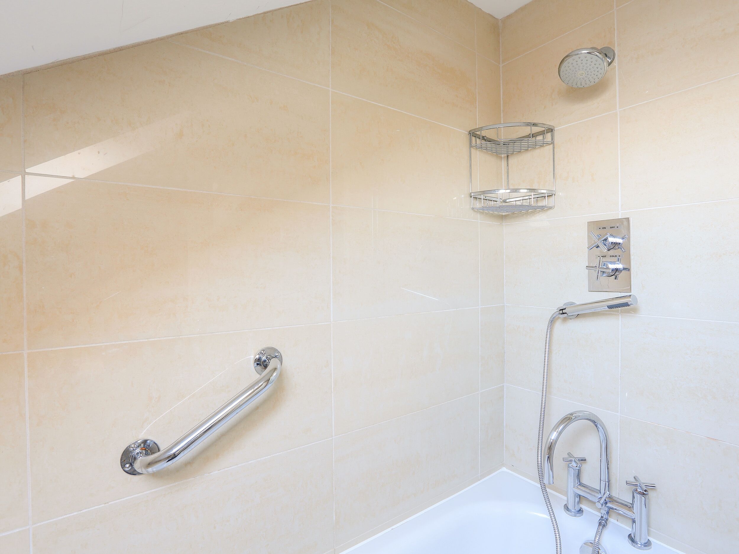 Ein Badezimmer mit einer Badewanne, einer Dusche, einer Handstange und einem Handtuchhalter.