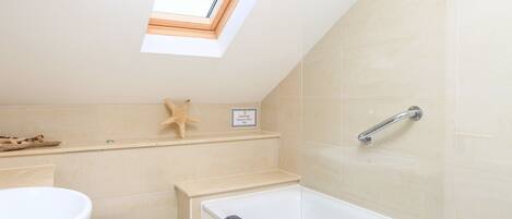 A bathroom with a skylight, a bathtub, a toilet, and a starfish decoration.