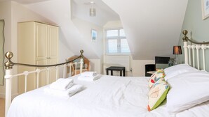 A bedroom with a bed, a wardrobe, a chair, a table, and a window. - 2 The Bay (Kingsbridge)