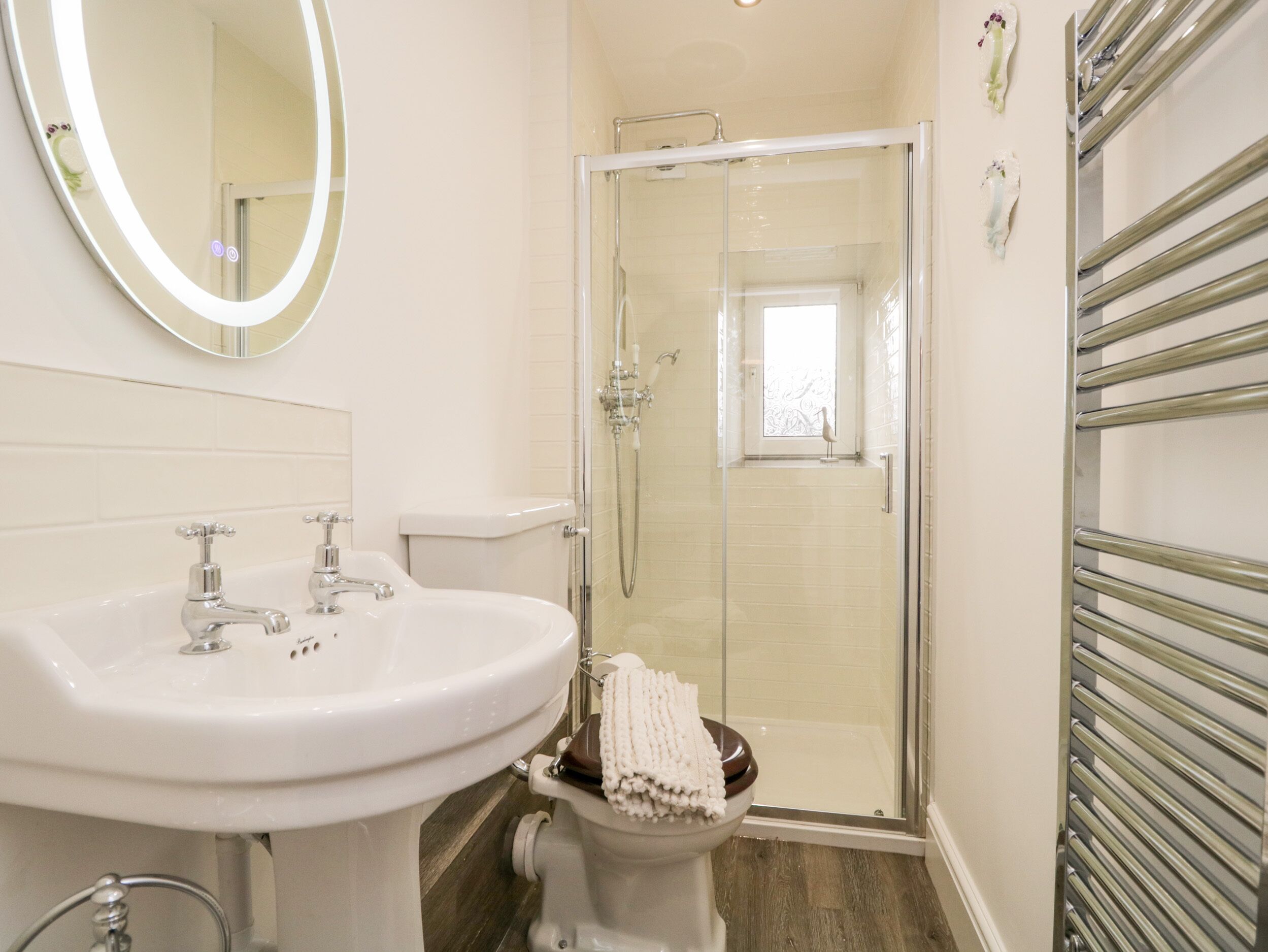 Une salle de bain avec un lavabo blanc, des toilettes et une douche fermée par une paroi de verre.