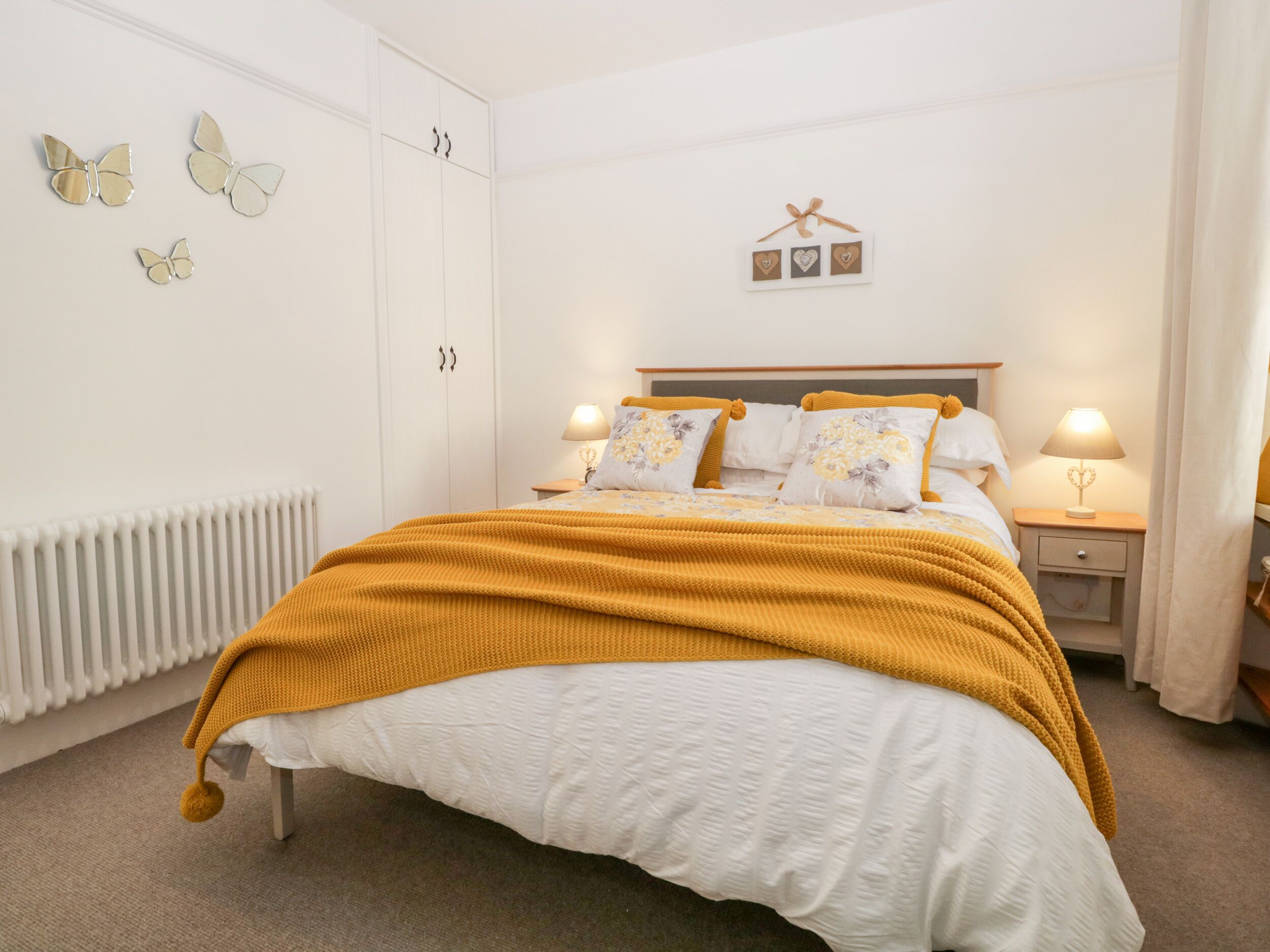 A bedroom with a bed, bedside tables, a radiator, and wall decorations.