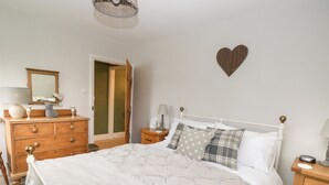 Una camera da letto con un letto, una cassettiera in legno, comodini e una decorazione a forma di cuore sulla parete.