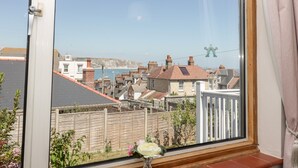 A view from a window overlooking a residential area with houses, a wooden fence, and a clear sky. - Seaview (Swanage)