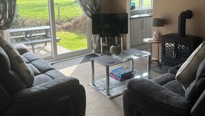 Un salon comprenant un canapé, une table basse en verre, un téléviseur et une cheminée.