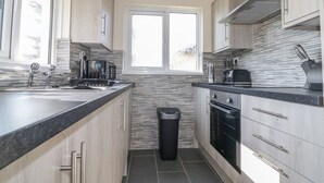 Une cuisine moderne dotée d’une grande fenêtre, d’appareils électroménagers en acier inoxydable et de meubles de rangement en bois clair.