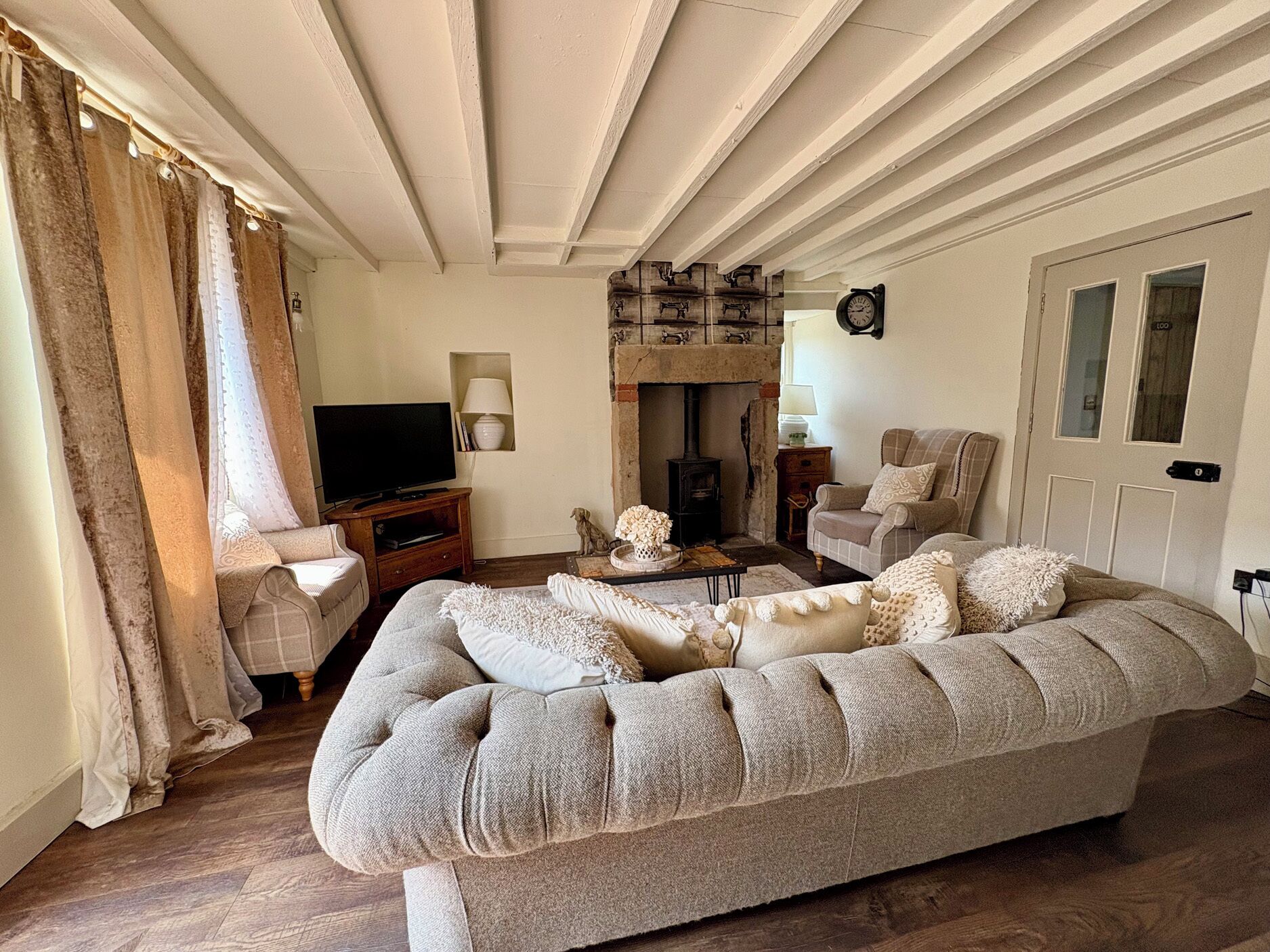 Een woonkamer met een bank, een televisie, een open haard en een klok aan de muur.