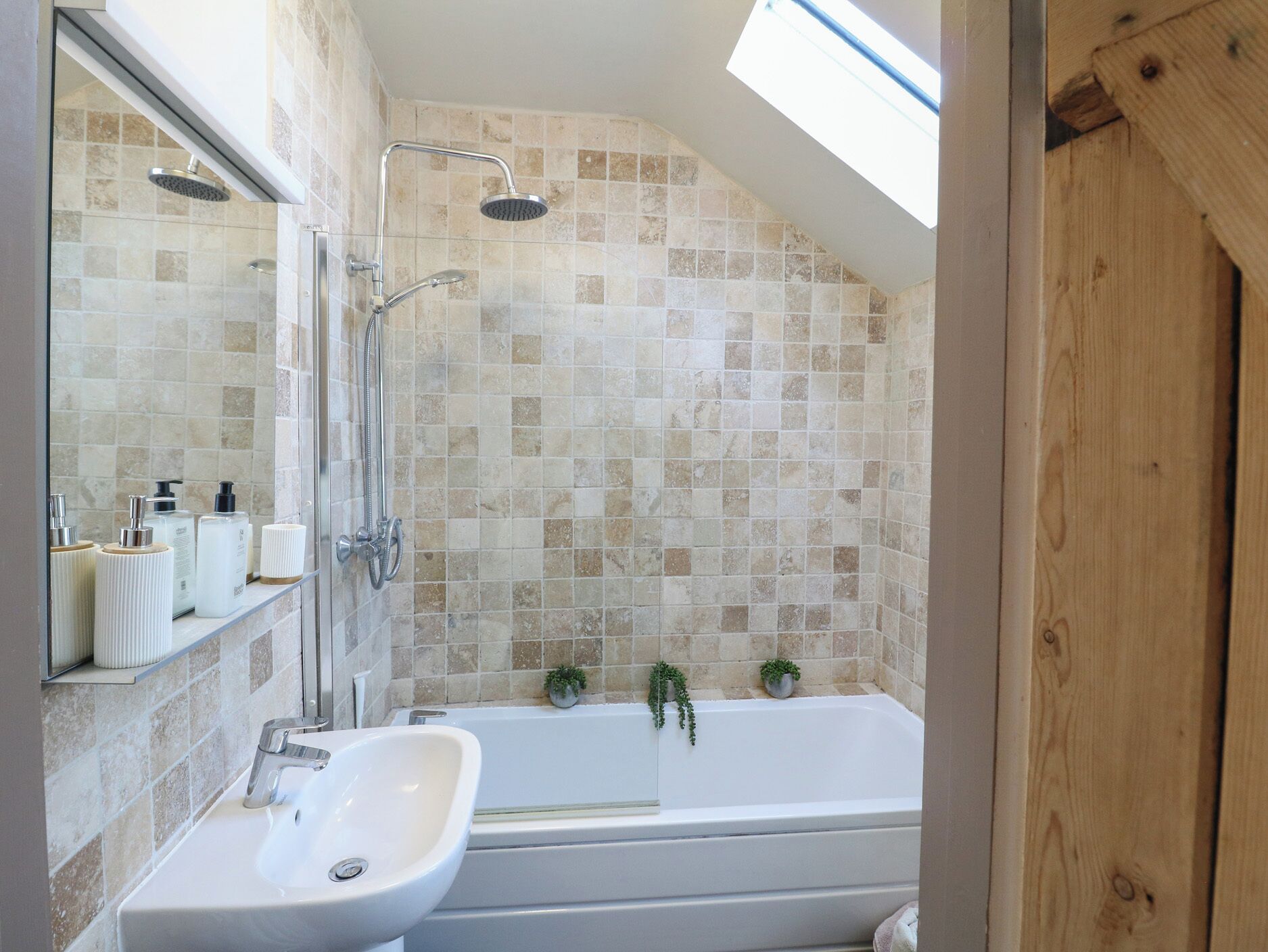 Un baño moderno con tragaluz, bañera, ducha y lavamanos.