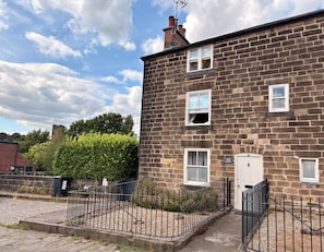 A two-story stone building with a brick facade, a white door, and a small window. - Coupling Cottage (Belper)