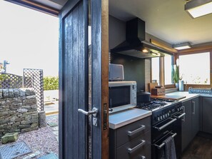 Una cocina moderna con microondas, estufa y horno integrados, que presenta una pared de piedra y vistas al exterior.