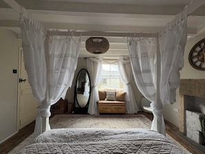 A bedroom with a four-poster bed, a mirror, a sofa, and a fireplace. - Coupling Cottage (Belper)