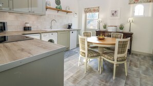Une cuisine moderne dotée d’un îlot central, d’appareils électroménagers intégrés et d’un coin repas avec des chaises à carreaux.