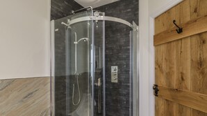Une salle de bain moderne avec une douche en verre, une porte en bois et un sol carrelé en marbre.
