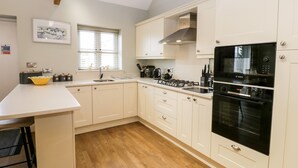 Une cuisine moderne avec des meubles blancs, un four noir de la marque Bosch et un plancher en bois.