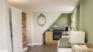 Une cuisine avec un mur en briques, une horloge et un lave-linge.