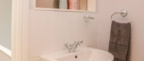 A bathroom with a white sink, a mirror, and a towel rack.