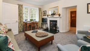 A living room with a fireplace, a dining table, and a sofa. - Middle Cottage - Tarvit (Cupar)