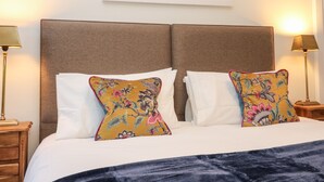 A neatly made bed with two pillows, a framed painting above, and bedside lamps on either side. - Middle Cottage - Tarvit (Cupar)