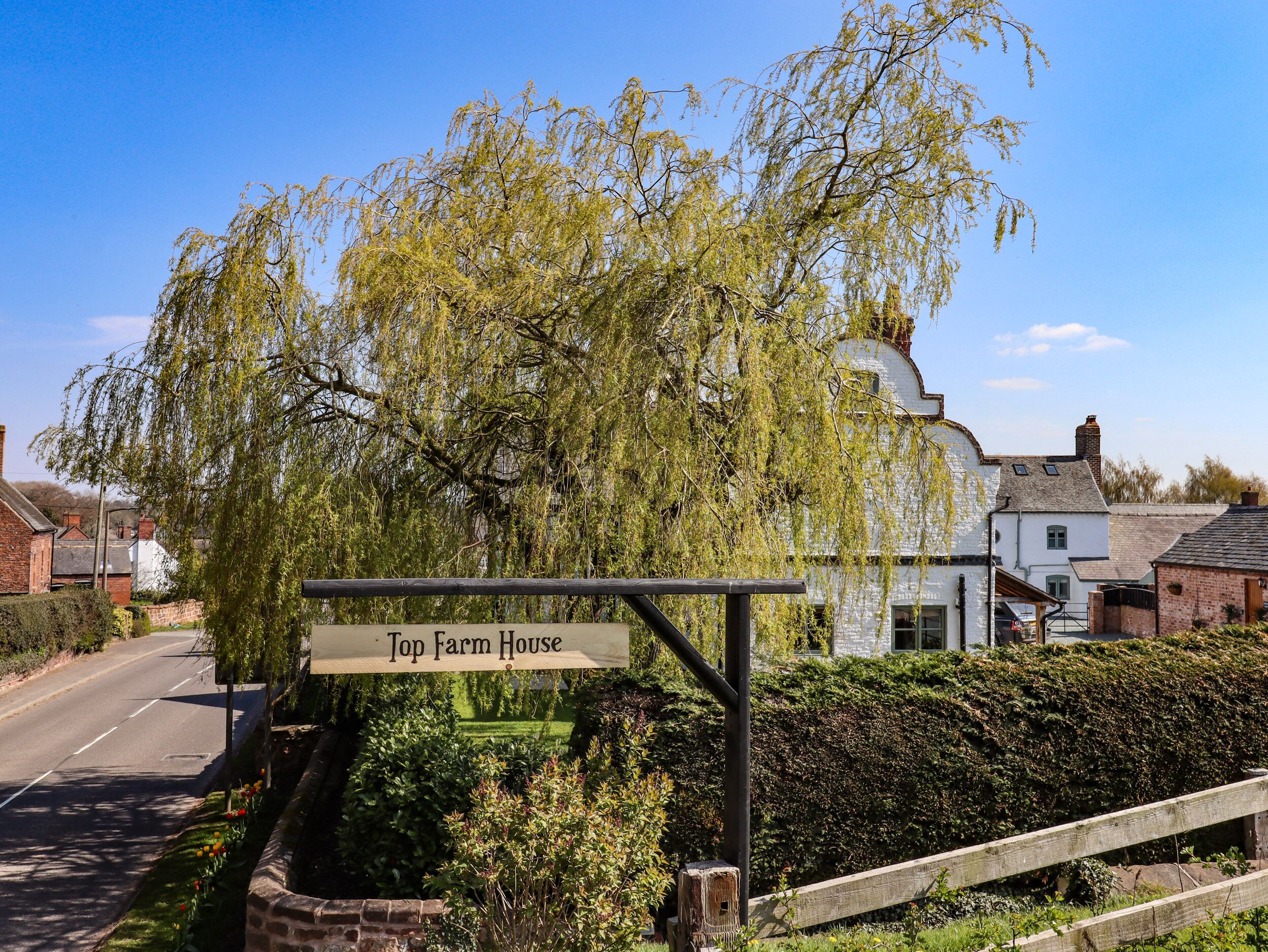 A sign for 'Top Farm House' with a white building in the background.