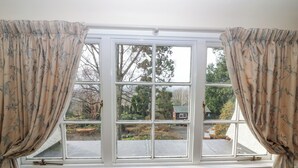 Una habitación con un ventanal, cortinas y una silla.