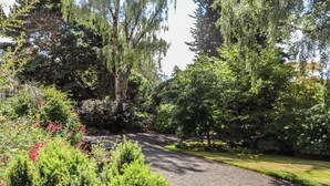 A gravel pathway surrounded by dense greenery and trees. - Branklyn Garden Cottage (Perth)