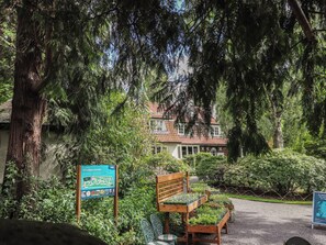 A garden with a wooden bench, a signboard, and a house in the background. - Branklyn Garden Cottage (Perth)
