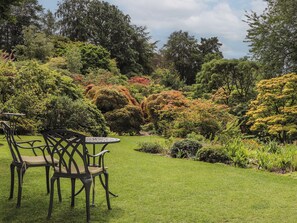 A garden with a table and chairs, surrounded by various trees and shrubs. - Branklyn Garden Cottage (Perth)