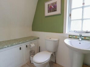 A bathroom with a toilet, sink, and a framed picture on the wall. - Branklyn Garden Cottage (Perth)