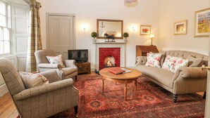 Una sala de estar con chimenea, dos sofás, una mesa de centro y un televisor.