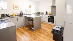 A modern kitchen with a central island, built-in appliances, and a wooden floor. - The Bull Inn (Caernarfon)