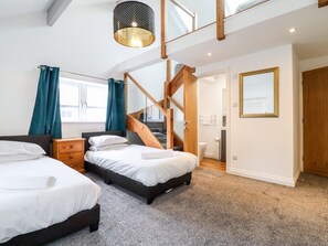Un dormitorio con dos camas, una escalera de madera, un baño y un ventanal grande.