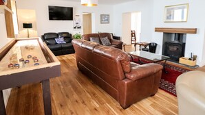 A living room with a billiards table, a brown leather sofa, a fireplace, and a television mounted on the wall. - The Bull Inn (Caernarfon)