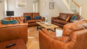 A spacious living room with leather sofas, a coffee table, and a remote control on the floor. - Pheasant's Roost (Hull)