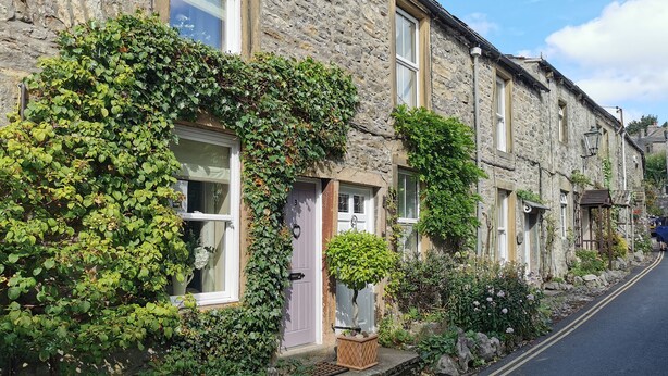 A row of stone houses with ivy-covered walls and a narrow street. - End Cottage (Skipton)
