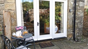 A patio with a table, chairs, and a white door with glass panels. - End Cottage (Skipton)