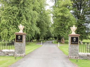 Un camino que conduce al Castillo de Stobo, con pilares de piedra y un escudo.