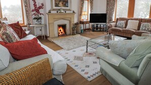 A cozy living room with a fireplace, comfortable seating, and a television. - Torview House (Peebles)