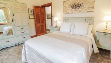 Une chambre à coucher avec un grand lit, une commode, un miroir et un tableau accroché au mur.