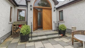 A building with a wooden door and a small porch with steps leading up to it. - Torview House (Peebles)