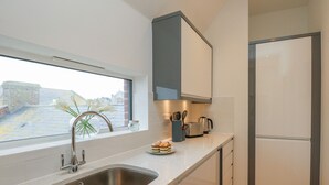 Una cocina moderna con un lavamanos de acero inoxidable, un tostador y una tetera sobre la encimera.