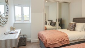 Un dormitorio con una cama, un escritorio, una silla y un espejo grande.
