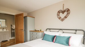 A bedroom with a bed, a dresser, a wardrobe, a mirror, and a heart-shaped decoration on the wall. - Owl's Hoot (Hull)