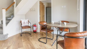 A modern living room with a staircase, a round dining table, leather chairs, and a fire extinguisher. - Owl's Hoot (Hull)