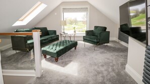 A loft bedroom with a skylight, green upholstered furniture, a grey carpet, and a large window with a view. - Owl's Hoot (Hull)