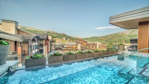 Una piscina amb vista a una muntanya i edificis al fons.