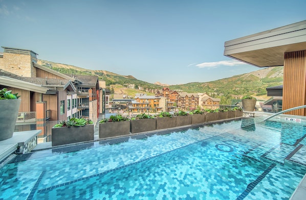 A swimming pool with a view of a hotel complex and mountains in the background.