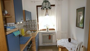A compact kitchen with blue cabinets, a small dining table, and a radiator.