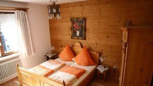 A wooden-paneled bedroom with a bed, two nightstands, a dresser, and a window with curtains.