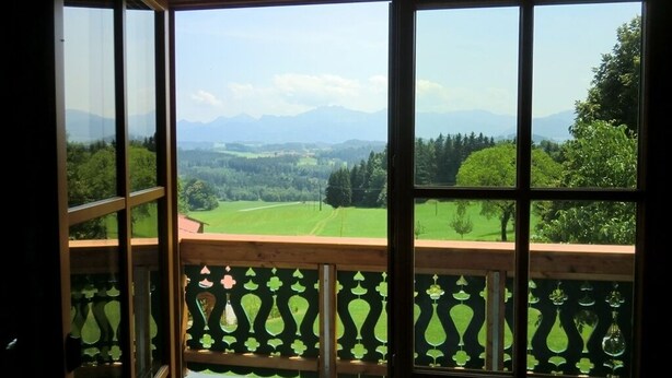 A room with large windows offering a view of a green landscape and mountains. - Five-star comfort vacation apartment Sternenstadl with balcony allergy-friendly (Rimsting)